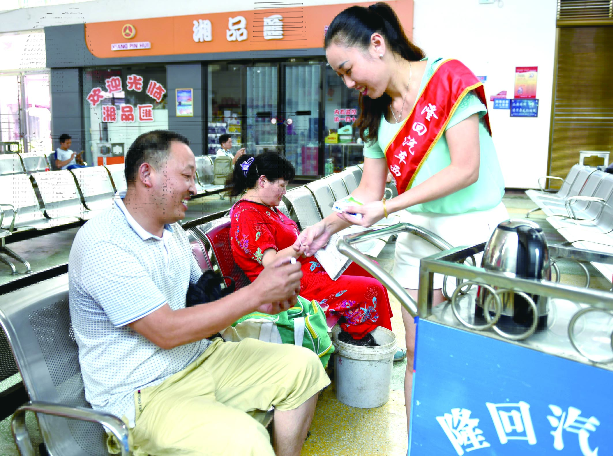 隆回分公司汽車西站工作人員正在為旅客免費(fèi)贈(zèng)送藿香正氣水。
