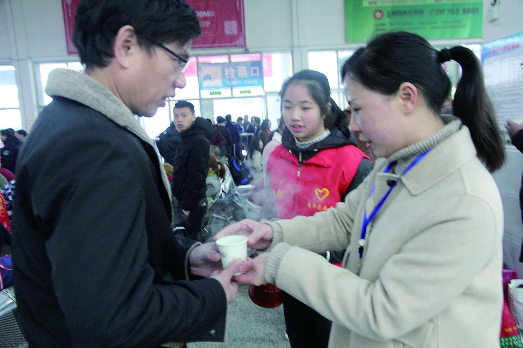 母女服務(wù)春運 2月13日，記者在新邵分公司汽車站看到，該分公司安全科副科長李喜梅與其在新邵一中初中部1701班就讀女兒劉嘉怡在車站擔(dān)當(dāng)志愿者。李喜梅在候車室耐心為旅客釋疑解惑，劉嘉怡為旅客遞上一杯杯熱茶，有時母女也相互合作，其樂融融。 祖冠 攝影報道